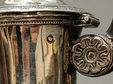 a silver tea pot with a handle on a table
