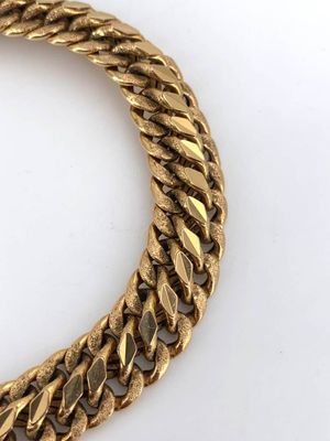 a close up of a gold chain bracelet on a white surface