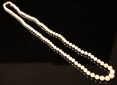 a close up of a pearl necklace on a black surface