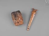 two carved wooden items on a gray surface with a wooden stick