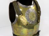 une armure dorée et argentée exposée sur fond blanc