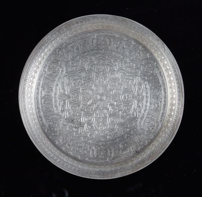 une vieille assiette en argent ornée d'un motif sur fond noir