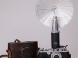 un appareil photo et un petit ventilateur posés sur une table blanche