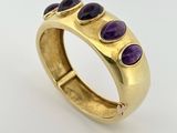 un gros plan d'une bague en or sertie de pierres violettes