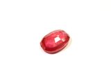 a close up of a red ruby stone on a white surface