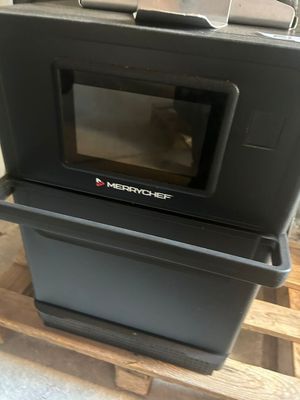 un micro-ondes posé sur une caisse, elle-même posée sur une palette