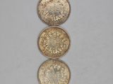 three gold coins sitting on top of each other on a white surface