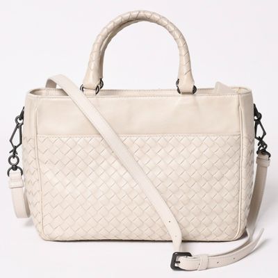 a white handbag with a braid handle and a strap