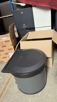 une poubelle posée à côté d'une autre poubelle dans une pièce