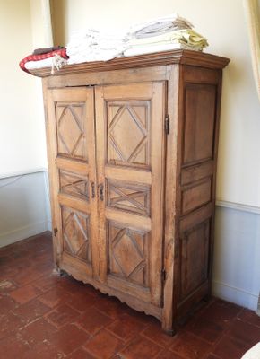 une grande armoire en bois sur laquelle sont posés de nombreux vêtements