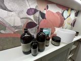 three bottles on a shelf next to a bowl and a cup