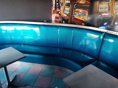 a blue booth with a table and two stools in front of it