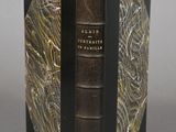 an old book with a black cover sitting on top of a table