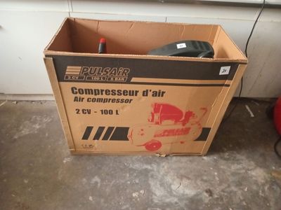 a cardboard box with a compressor in it sitting on the floor