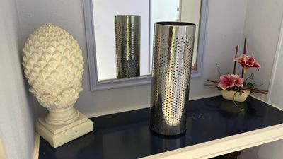 a vase on a table with a mirror in the background