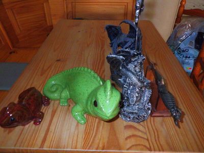 a green alligator statue sitting on a table next to a knife and a bag