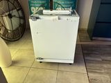 a small white refrigerator sitting on the floor in a room