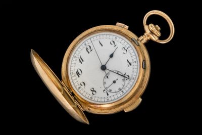 une montre de poche en or avec une chaîne, sur fond noir