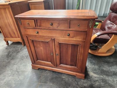 une commode en bois avec des tiroirs et une chaise à l'arrière-plan