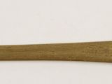 a gold spoon with a bird on it on a white surface