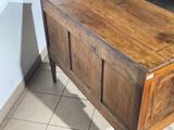 a wooden chest with a drawer underneath it on a tiled floor