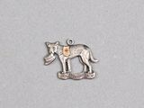 a close up of a metal dog charm on a white surface