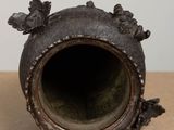 a metal vase with a bird decoration on it