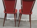 pair of red chairs with wooden legs and backrests