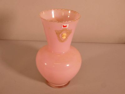 un vase rose orné d'un motif doré