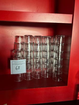 bottles and glasses are stacked on a shelf in a red room