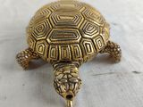 an antique brass turtle figurine sitting on a white surface