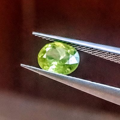un gros plan d'une pierre précieuse verte tenue par une paire de pinces