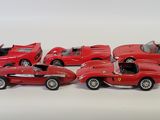 six red toy cars are lined up in a row on a white surface