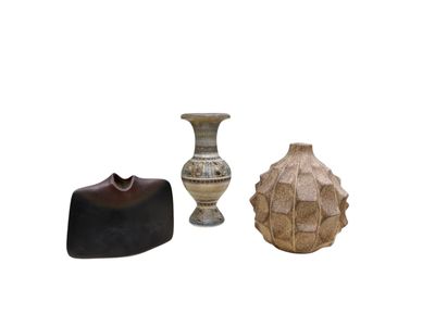 trois vases différents posés les uns à côté des autres sur une surface blanche