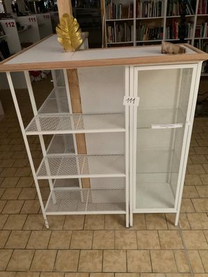 une armoire blanche avec des étagères, sur laquelle est posé un vase doré