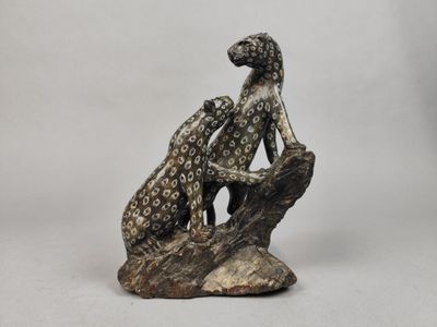 une statue représentant un chien et un chat assis sur un rocher