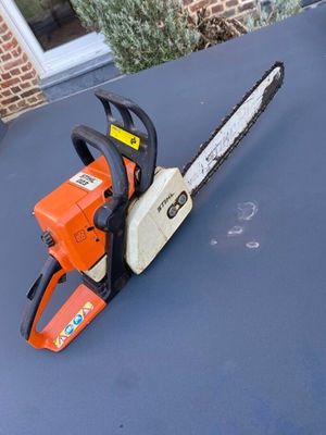 an orange and white chainsaw sitting on top of a blue table