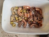 a white container filled with copper pipes and nuts
