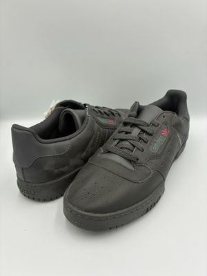 une paire de baskets en cuir noir avec un logo rouge et vert sur la semelle