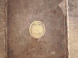 a brown book with a gold seal on it on a wooden table