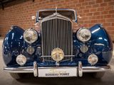 a blue car that is parked in front of a brick wall