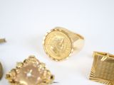several gold rings and a gold coin on a white surface