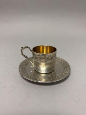 a silver cup and saucer on a saucer on a white surface