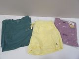 three pairs of yellow, green, and purple shirts on a white table
