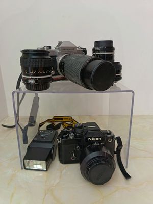 two cameras sitting on a clear shelf next to each other