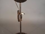 une lampe à l'ancienne posée sur un pied en métal, posée sur une surface blanche