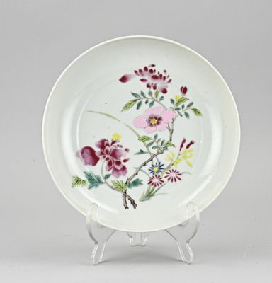 une image représentant une assiette posée sur un socle, sur laquelle sont peintes des fleurs