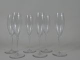 four empty wine glasses are lined up on a white surface