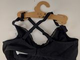 a black bra top on a hanger on a white wall
