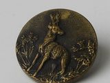 un bouton en bronze orné d'un cerf sur un fond blanc